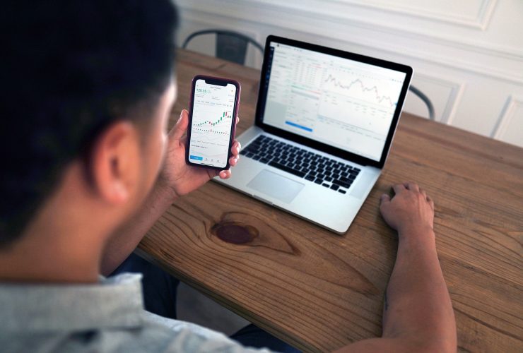 forex trader trading on a smartphone and laptop